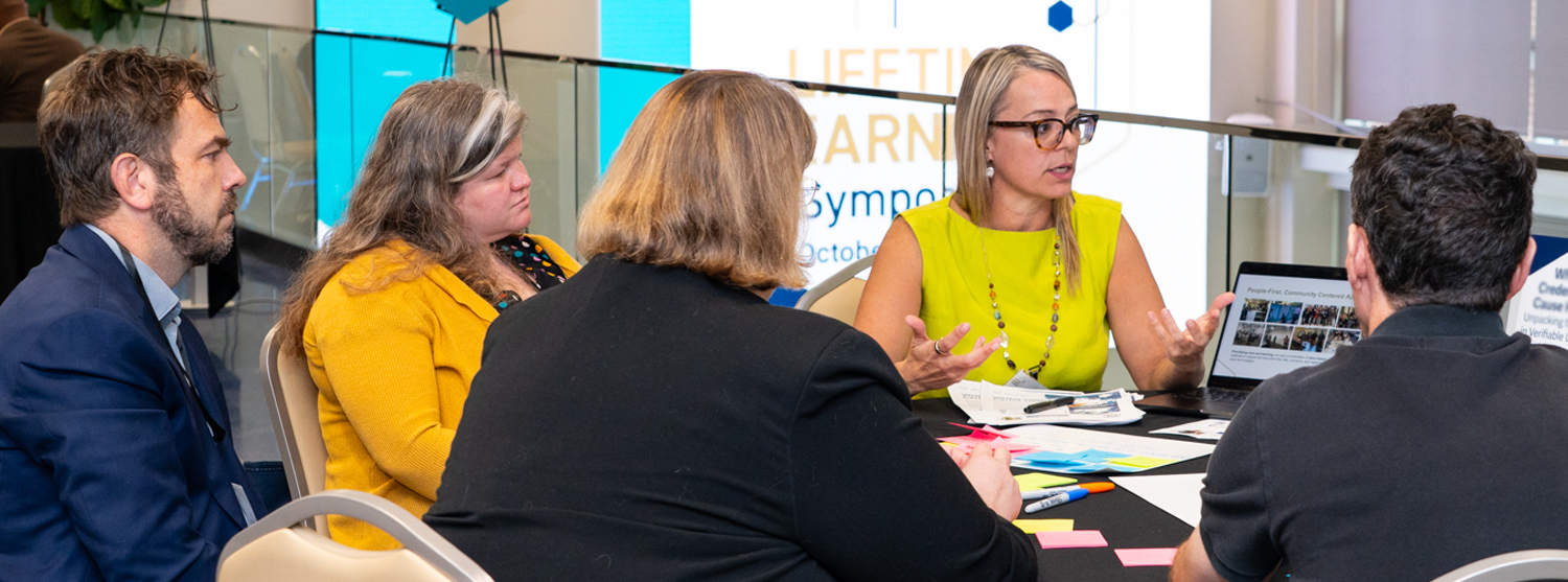 A woman speaks at a roundtable discussion regarding credentials in higher education