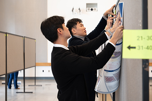 two men work together to hang up information at an educational conference